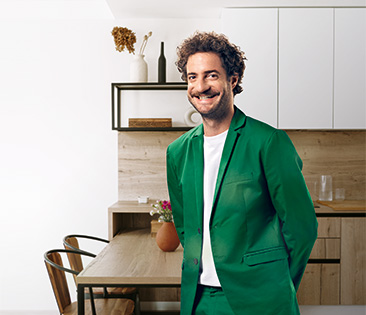 Hausratversichetung: Mann in grünem Anzug steht in Wohnküche